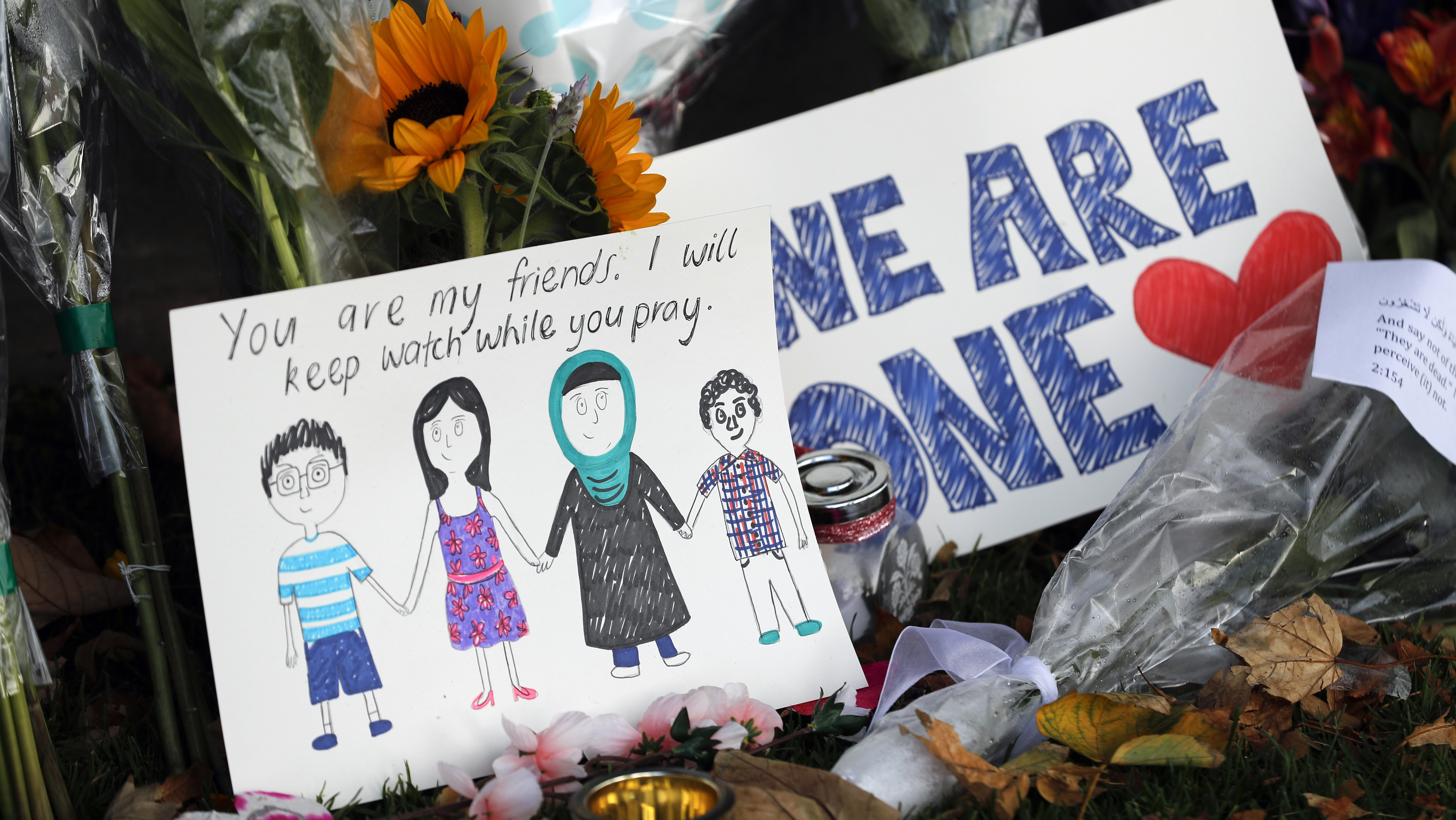 A Message Card Is Placed At A Collection Of Flowers Left At The